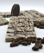 Close-up of several STEM Cookies & Cream Mushroom Chocolate Bars garnished with crumbled pieces of chocolate cookies. There are whole chocolate sandwich cookies placed among the bars, all set against a white background.